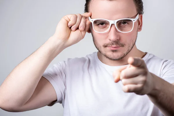 Przystojny mężczyzna z okularami pokazuje palec do przodu na białym plecach — Zdjęcie stockowe