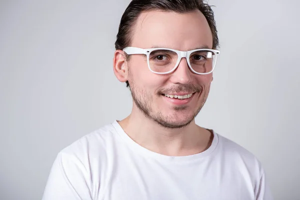 Hombre guapo con cerdas y gafas sonriendo en un fondo blanco —  Fotos de Stock