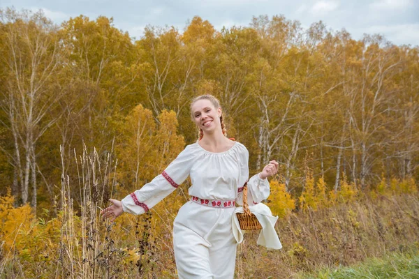 Beautiful girl in a traditional Slavic dress with a straw basket — Stock Photo, Image