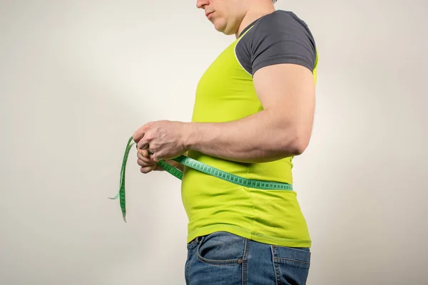 Un hombre en jeans y una camiseta con el vientre gordo sobre un fondo blanco — Foto de Stock