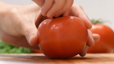 Kadın elleri ahşap bir tahta üzerinde metal bir bıçak ile salata için domates kesme