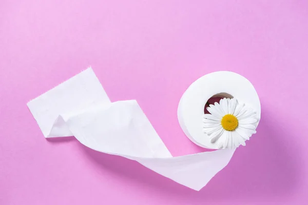 Papel higiénico perforado blanco con el aroma y la margarita en un rosa — Foto de Stock