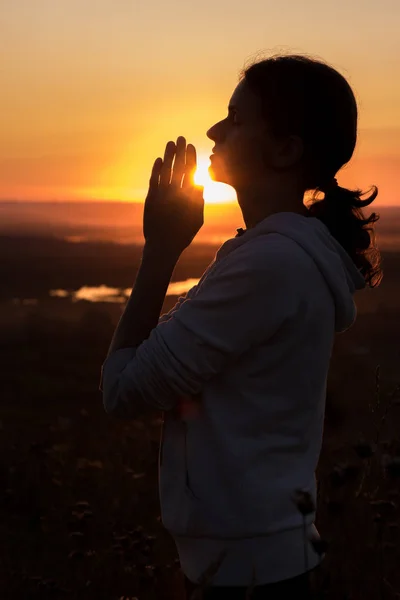 Bella donna che prega al tramonto contro il cielo in estate — Foto Stock