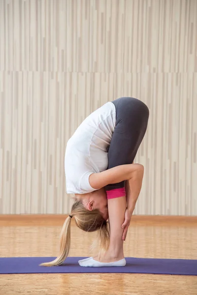 Hermosa chica rubia practica yoga asanas y se estira en una r — Foto de Stock