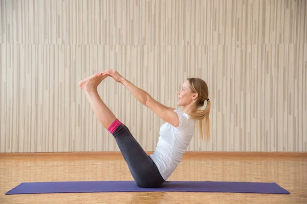 Hermosa chica rubia practica yoga asanas y se estira en una r — Foto de Stock