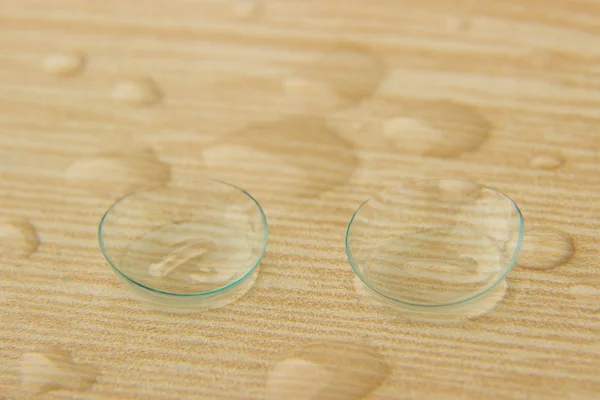 Kontaktní čočky pro oči kapkami roztoku na dřevěný stůl — Stock fotografie