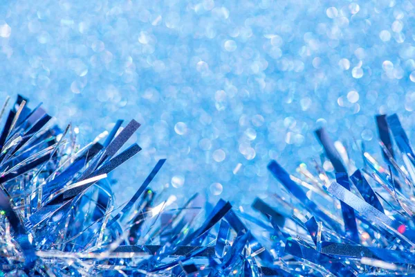 Beautiful blue tinsel on glitter background for festive design. Royalty Free Stock Images