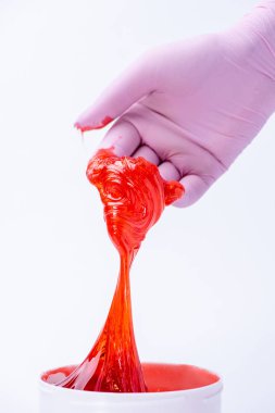 Bir eldiven kadın eli depilat için kırmızı şeker hamuru veya balmumu tutar