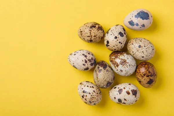 Красиві плямисті свіжі перепелині яйця на жовтому паперовому фоні — стокове фото