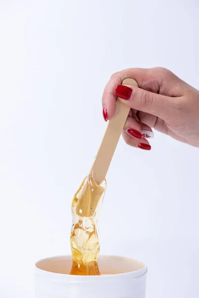 Liquid yellow sugar paste or wax for depilation on a stick close — Stock Photo, Image