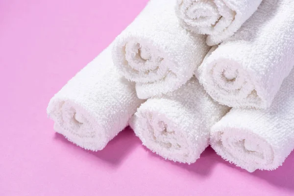 Toallas de rizo suavemente enrolladas para spa o masaje sobre un fondo rosa — Foto de Stock