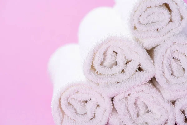 Gently rolled terry towels for spa or massage on a pink backgrou