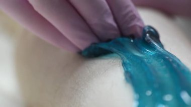 Bir kadının bacaklarındaki kılları ağda yaparak aldırma prosedürünün aşamalarından birine yakın çekim.