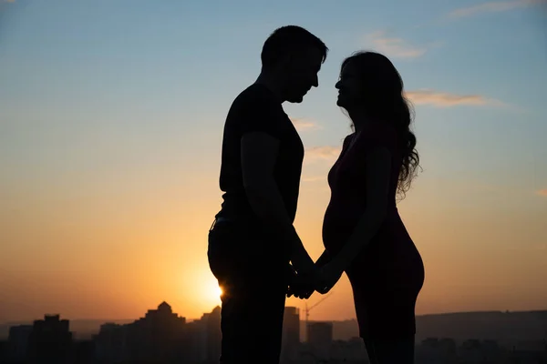 Silhouettes of a pregnant woman and her husband on the backgroun — Stock Photo, Image