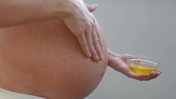 妊娠中の少女のクローズアップ摩擦油からストレッチマークへ彼女の腹の皮膚 — ストック動画