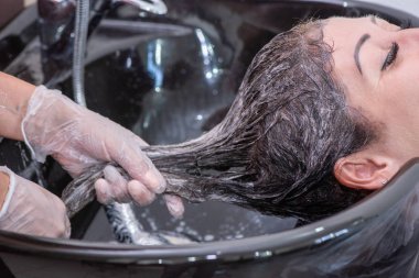 Siyah bir lavabonun içinde güzel bir esmer kadın tarafından kafa yıkama.