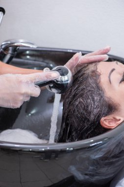 Siyah bir lavabonun içinde güzel bir esmer kadın tarafından kafa yıkama.