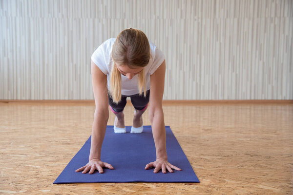 The girl practices yoga in the gym and stands on the arms in the exercise plank