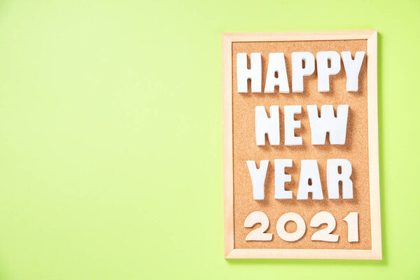 Надпись с гипсовыми буквами с Новым годом на пробковой доске и цифрами 2021 на зеленом бумажном фоне вид сверху с местом для текста