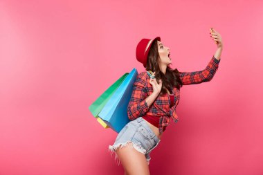 renkli alışveriş torbaları cep telefonuyla pembe arka plan, alışveriş ve indirim kavramı karşı olan mutlu kadın