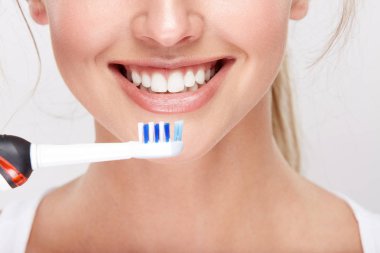 elektrikli diş fırçası, diş hekimliği kavramı holding beyaz dişler ile gülümseyen güzel kadın