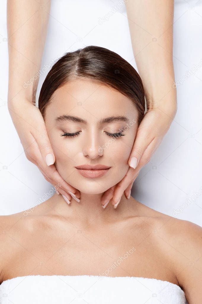 young woman with perfect skin having facial massage, hands on face, skin care, spa procedure and relaxing concept 