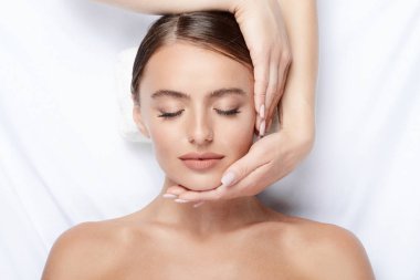 yüz, Cilt Bakımı, spa yordam ve rahatlatıcı kavramı üzerinde eller ile mükemmel cilt yüz masajı, sahip genç kadın 