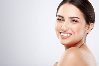 pretty smiling young woman with naked shoulders posing at grey background, beauty photo concept, skin care, hydrated skin clipart