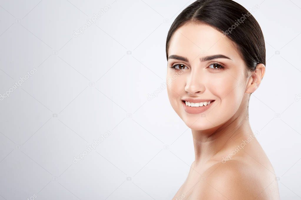 pretty smiling young woman with naked shoulders posing at grey background, beauty photo concept, skin care, hydrated skin