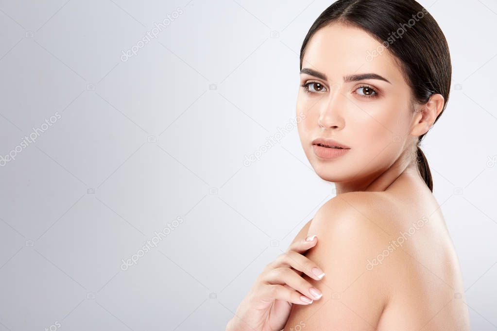 attractive young woman with dark hair and perfect skin posing at grey background, beauty photo and spa concept