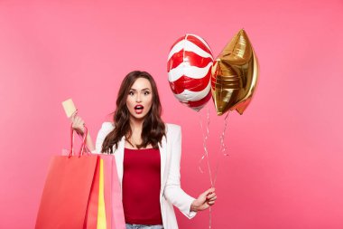 Alışveriş torbaları ve pembe arka plan, alışveriş ve indirim kavramı karşı poz balon olan mutlu kadın