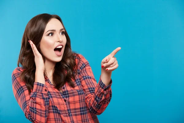 Nette Junge Frau Zeigt Auf Etwas Vor Blauem Hintergrund — Stockfoto