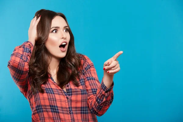 Nette Junge Frau Zeigt Auf Etwas Vor Blauem Hintergrund — Stockfoto