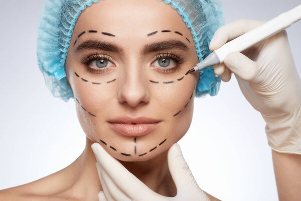 портрет привлекательной женщины, концепция пластической хирургии. Модель с проколами на лице, руки в перчатках
