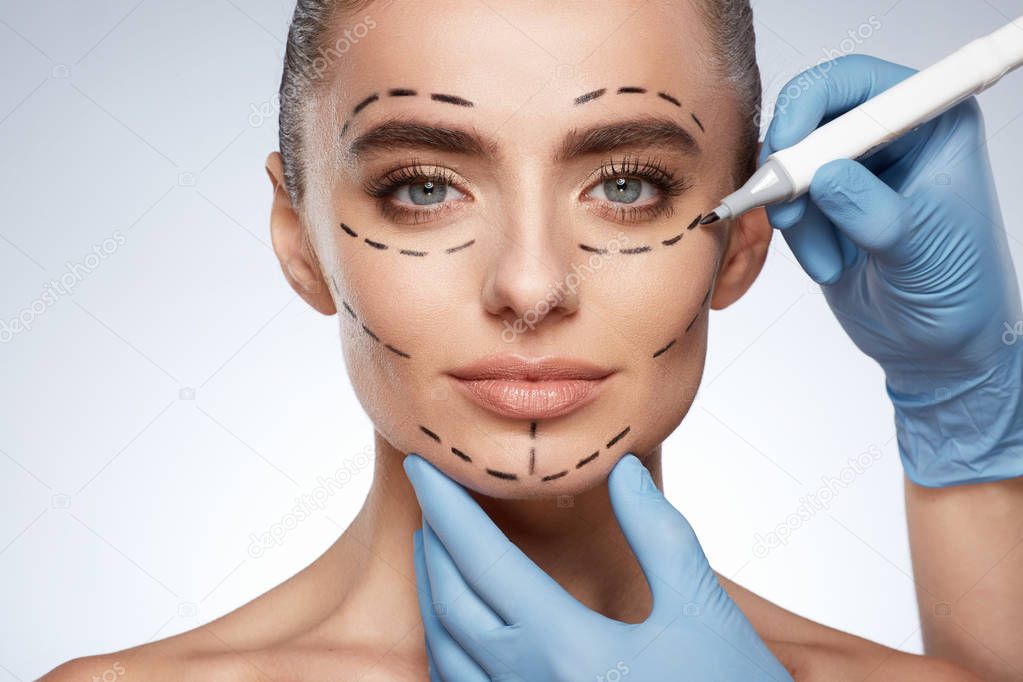beauty portrait of attractive woman, plastic surgery concept. Model with puncture lines on face, hands in gloves drawing