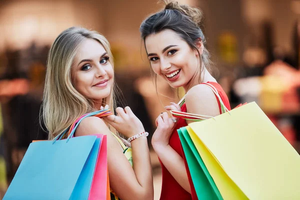 快乐的年轻妇女与五颜六色的购物袋在购物中心 — 图库照片