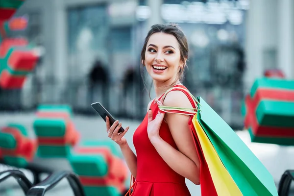 Bela Morena Jovem Com Sacos Compras Coloridos Usando Telefone Celular — Fotografia de Stock