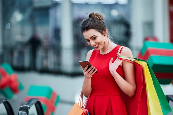 beautiful brunette young woman with colorful shopping bags using mobile phone, online shopping concept