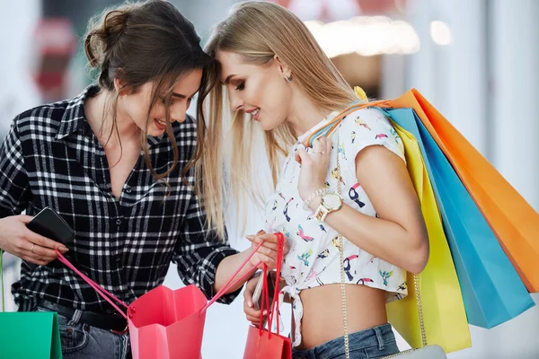快乐的年轻妇女与五颜六色的购物袋走在购物中心 — 图库照片