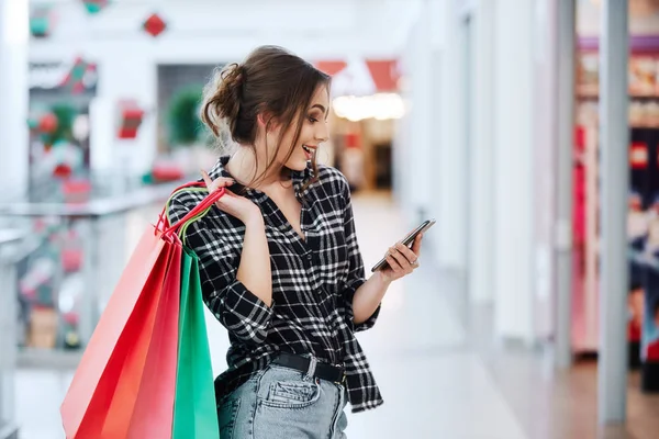 カラフルなショッピング バッグ携帯電話を使用して オンライン ショッピングのコンセプトと美しいブルネットの若い女性 — ストック写真