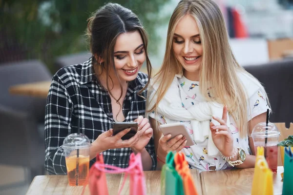 akıllı telefonlar, kafede masada çanta alışveriş renkli kullanarak çekici genç kadın