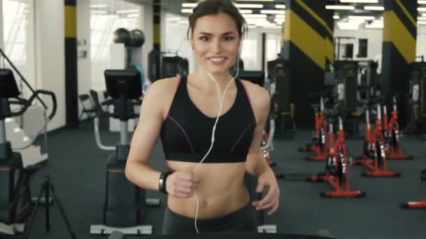 Chica en forma encantadora corriendo en el fondo del gimnasio — Vídeos de Stock