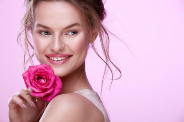 pembe arka plan üzerinde poz pembe gül ile çekici genç kadın portresi