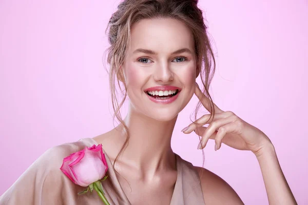 ピンクの背景にポーズピンクのバラを持つ魅力的な若い女性の肖像画 — ストック写真