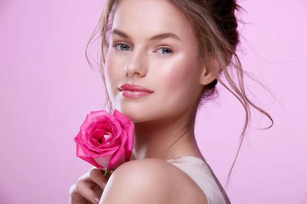 portrait of attractive young woman with pink rose posing on pink background