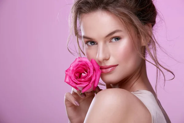 portrait of attractive young woman with pink rose posing on pink background