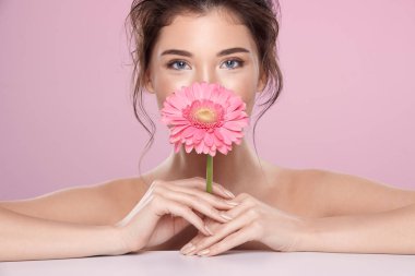 woman with pink flower and bare shoulders on pink background