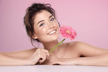 woman with pink flower and bare shoulders on pink background