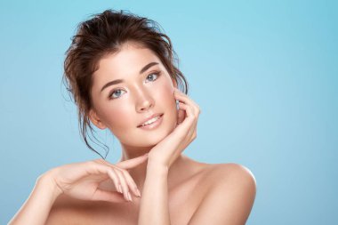 young attractive woman with bare shoulders on blue background