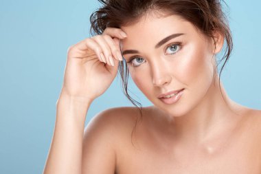 young attractive woman with bare shoulders on blue background